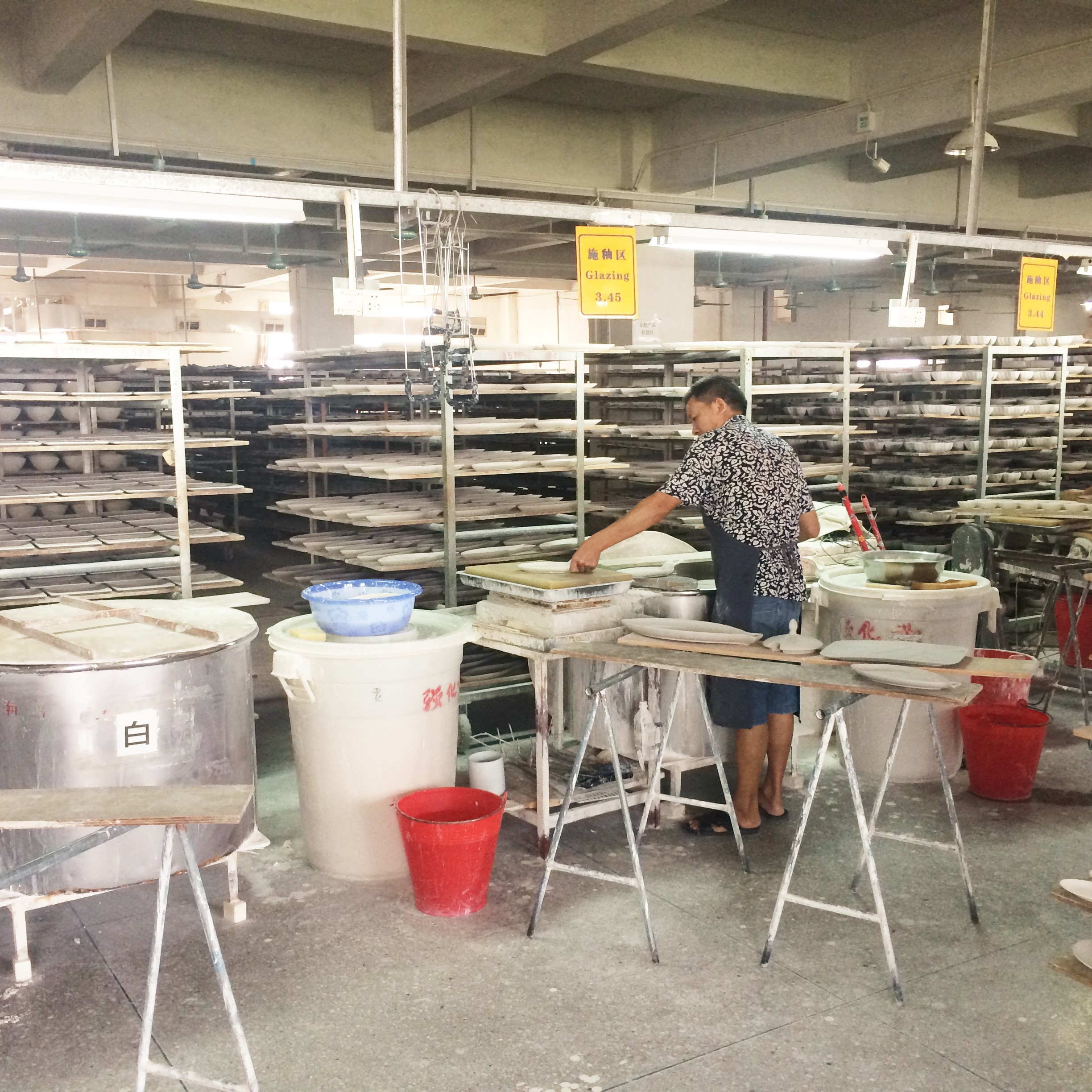 A worker at a ceramic factory in Chaozhou preparing dinnerware for glazing.